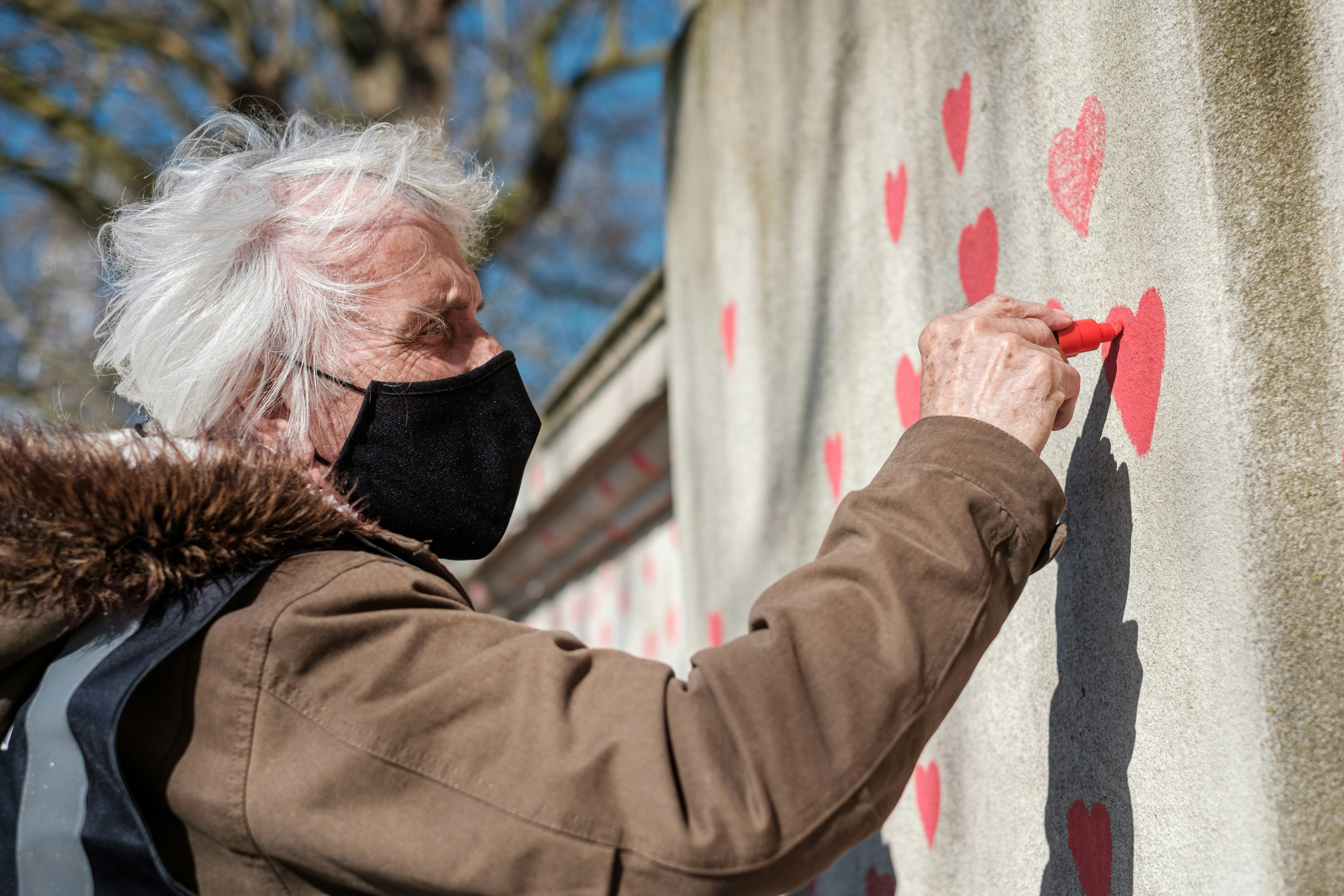 man in brown jacket holding red paint on white wall